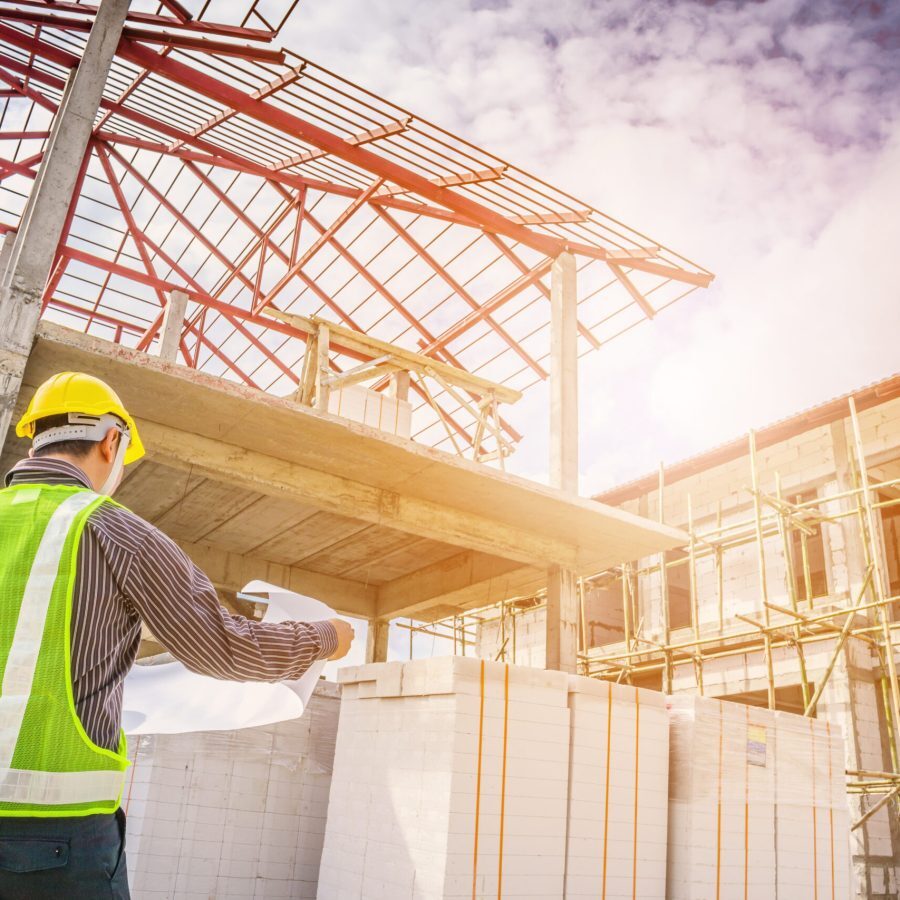 Asian business man construction engineer worker in protective helmet and blueprints paper on hand at house building site