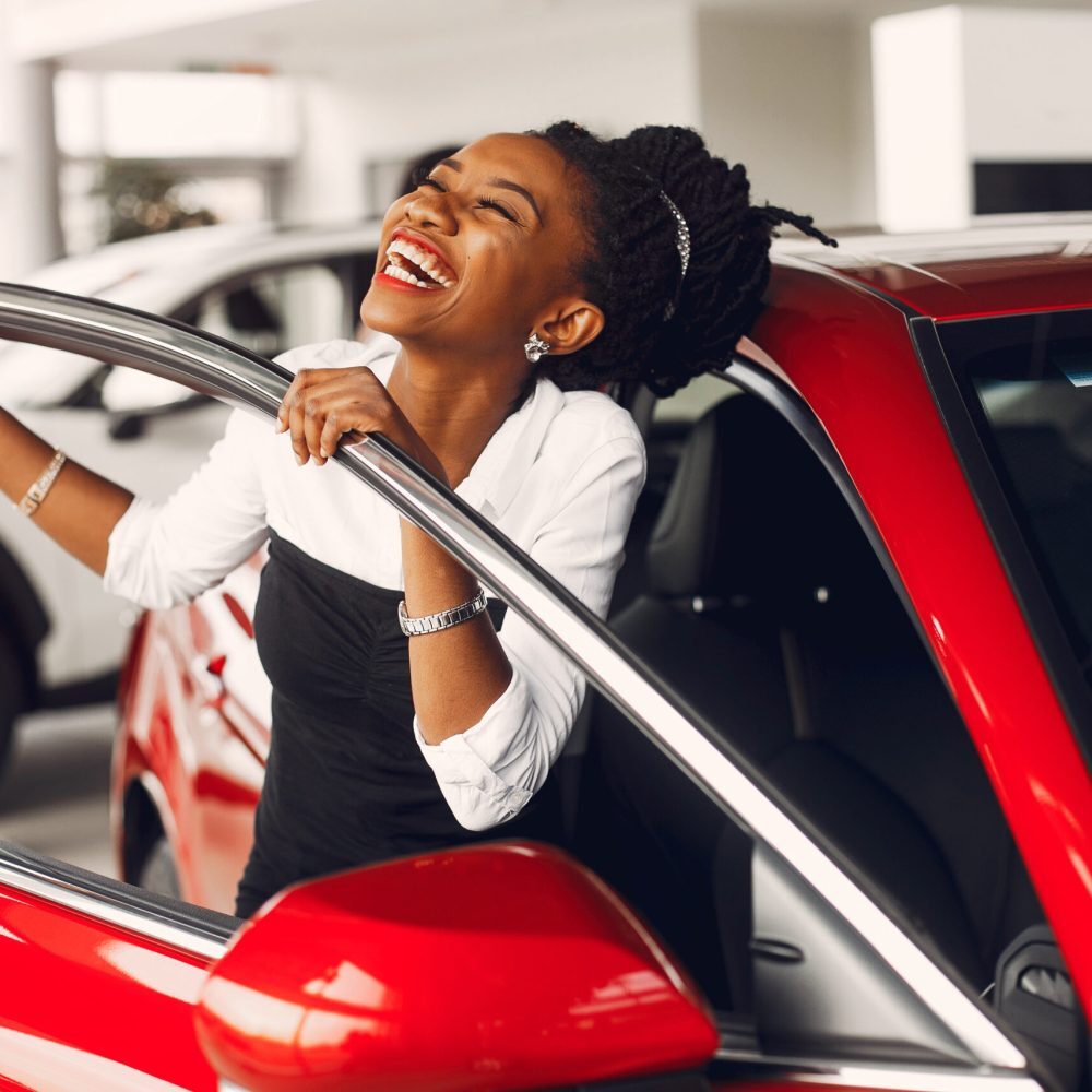Woman buying the car. Lady in a car salon. Elegant black girl